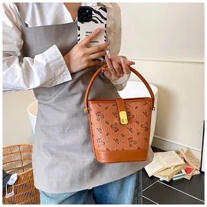 Sac seau marron avec imprimés ours et fermoir rotatif doré porté par une femme mannequin