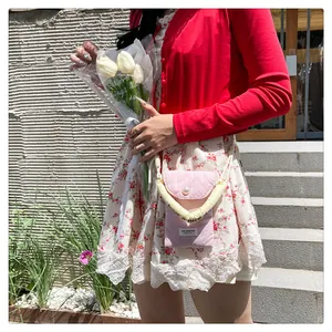 Detail of pink cotton crossbody phone bag with pearl buckle and yellow rope strap
