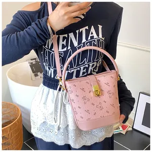 Détail du sac seau rose avec motifs d'ours, fermoir doré et texture en cuir de litchi