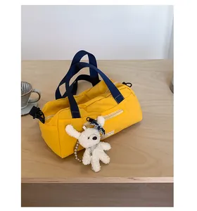 Dettaglio di borsa sportiva gialla con tracolla blu e ciondolo a forma di orsetto