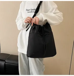 Dettaglio della grande borsa tote nera con chiusura a coulisse e tracolla plissettata