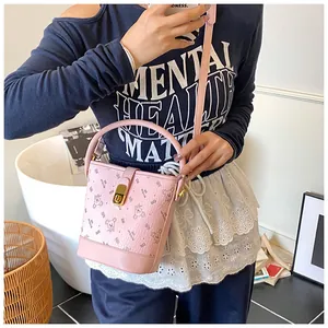 Sac seau rose avec imprimé ours et fermoir tournant doré présenté dans un décor lifestyle