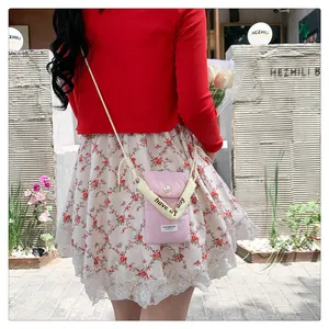 Detailed view of pink phone bag with white pearl buckle and Stay Positive label