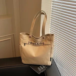 Borsa tote in tela beige con scritte marroni e tasca frontale con zip in interno