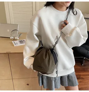 Dettaglio di una borsa a secchiello bicolore con chiusura a coulisse indossata da modella