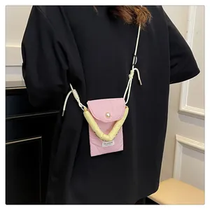 Pink quilted phone bag with lemon yellow handle and Stay Positive tag on a black shirt