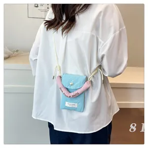 Detail of light blue fabric phone bag with pink padded handle and pearl button closure