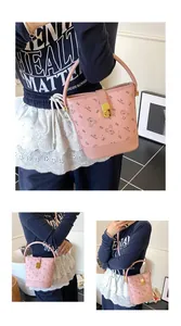 Détail du sac seau rose avec imprimé ours, cuir grainé et fermoir rotatif doré élégant