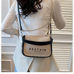 Detailed view of beige canvas crossbody bag with black leather trim and printed text