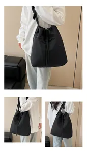 Dettaglio della borsa a secchiello in nylon nero con coulisse e fibbie in metallo