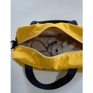 Borsa a tracolla in nylon giallo con manici blu scuro e ciondolo orsetto di peluche