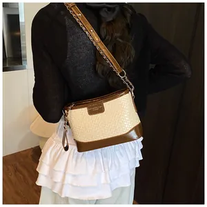 Dettaglio della trama intrecciata beige e pelle marrone caffè sulla borsa a secchiello