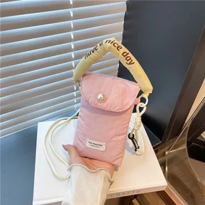 Quilted pink nylon phone bag with yellow handle and large pearl accent in hand