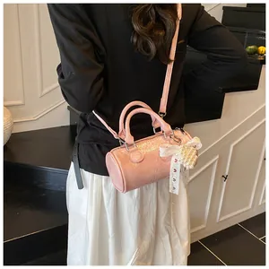 Borsa a cilindro rosa con texture lucida e ciondolo con fiocco di pizzo e perle