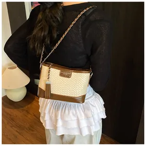 Dettaglio borsa a secchiello bicolore beige e marrone con frange e tracolla a catena