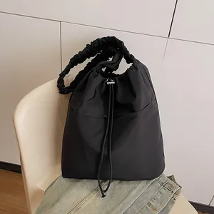 Borsa tote chic in nylon nero con tracolla arricciata appoggiata su una sedia