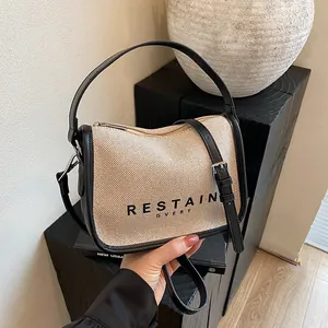Minimalist canvas shoulder bag with black leather trim and RESTAIN GVERY logo print