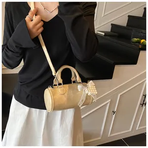 Dettaglio della borsa a cilindro beige con fiocco di pizzo e perle sulla modella
