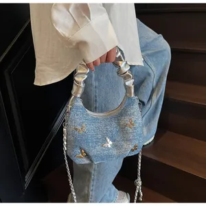 Dettaglio borsa a tracolla in denim con farfalle metalliche 3D e manico argentato