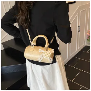 Dettaglio della borsa mini boston beige con fiocco in pizzo e ciondolo a cuore