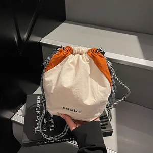 Borsa a secchiello bicolore panna e arancione con elegante tracolla in tessuto