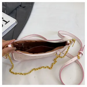 Détail du sac bandoulière rose clair montrant la doublure, la poche zippée et la chaîne dorée