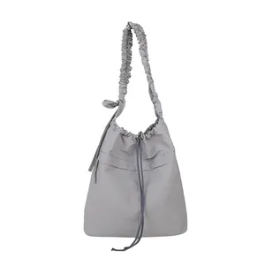 Borsa a secchiello grigia in nylon con coulisse, tracolla increspata e fiocchi laterali