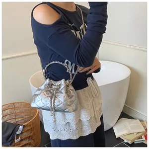 Detail of silver quilted bucket bag featuring drawstring closure with pearl accents