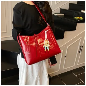 Detail of glossy red PU tote bag with shoulder straps and trendy blue astronaut charm