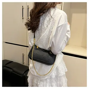 Détail du sac à bandoulière noir gaufré avec chaîne dorée sur mannequin en dentelle