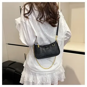 Vue détaillée du sac bandoulière en cuir gaufré noir avec motifs cartoon et chaîne dorée