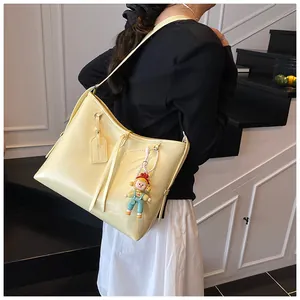 Detail of cream yellow large capacity tote bag with cute doll charm on white stairs