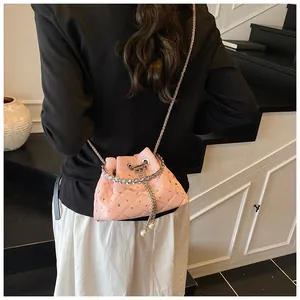 Macro view of pink quilted bucket bag with rhinestones, pearls and chain detail