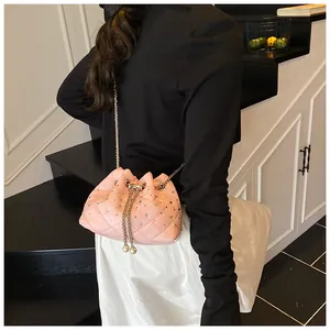 Detail shot of a pink quilted bucket bag with rhinestones, pearls, and a chain strap