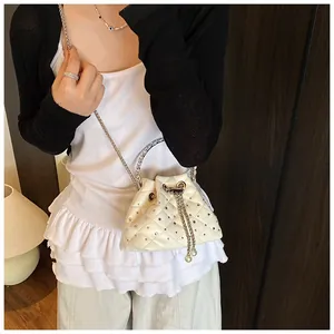 Detail of white quilted bucket bag with rhinestones, metal chain and pearl drawstring