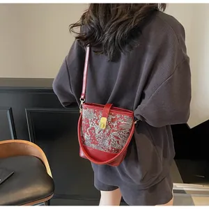 Detail of red Chinese embroidery bucket bag with silver beast pattern and gold buckle