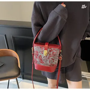 Detail of red water bucket bag with white dragon embroidery and gold buckle hardware