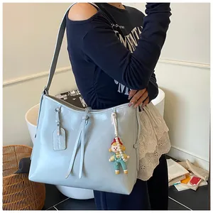 Detail of light blue faux leather tote bag with elegant decorative strap and cartoon pendant