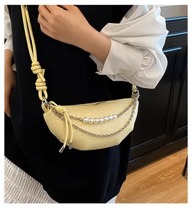 Dettaglio borsa gialla con trama a coccodrillo goffrata e catene decorative di perle e metallo