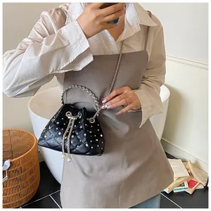 Black quilted drawstring bucket bag with sparkling rhinestones and pearl details on model