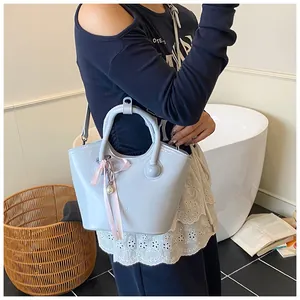 Detail of light blue bucket bag with glossy finish and pink ribbon bow pendant charm