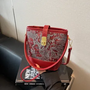 Elegant red embroidered bucket bag in Chinese style with golden hardware and leather strap