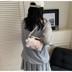 Dettaglio mini borsa a tracolla rosa con fiocco in pizzo e ciondolo a cuore con perla