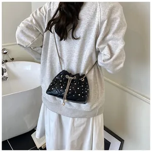 Quilted black bucket bag with silver rhinestones and chain strap on a model