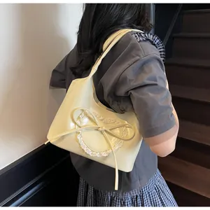 Dettaglio decorazione cuore in pizzo e fiocco su borsa tote in pelle PU crema