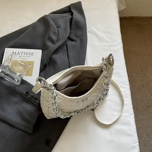 Borsa a tracolla trapuntata crema con catena argento e strass su biancheria da letto
