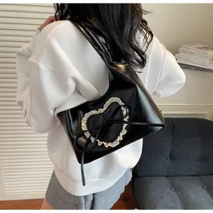 Dettaglio della borsa tote nera con toppa a cuore in pizzo bianco e fiocco in pelle PU