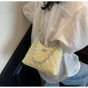 Dettaglio della borsa a spalla gialla trapuntata con strass e catena argentata
