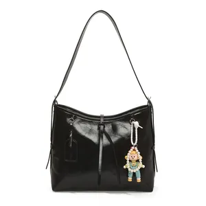 Minimalist black glossy tote bag with cartoon doll pendant and thin shoulder strap