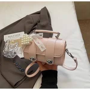 Dettaglio borsa a mano cilindrica rosa chiaro con ciondolo cuore di perle e fiocco di pizzo
